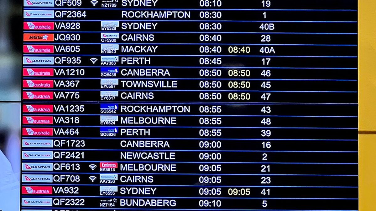 A domestic departures board at an airport terminal listing flight numbers, destinations, gates and status