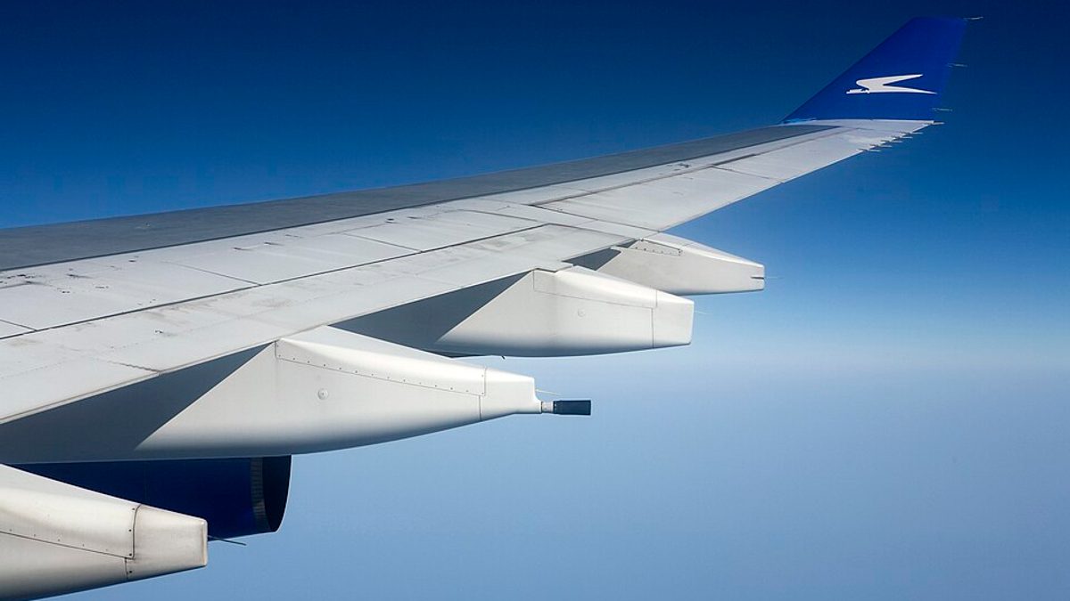 View of an aircraft wing through a cabin window in flight