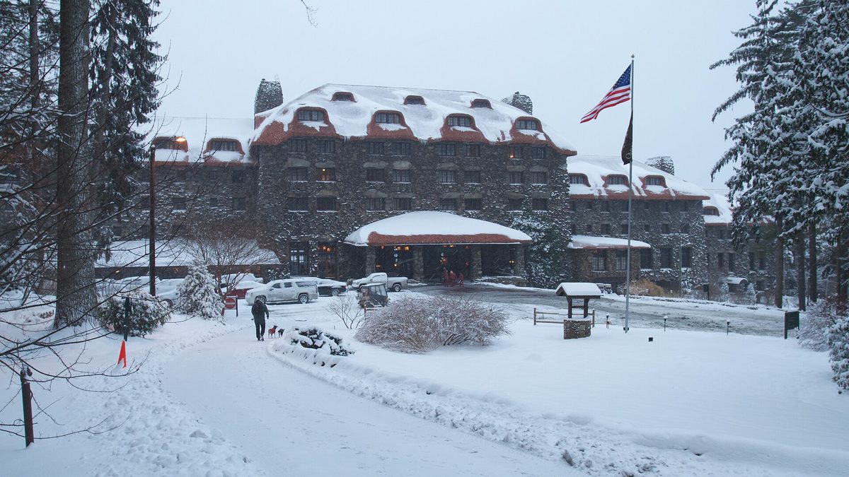 The Omni Grove Park Inn in Asheville, North Carolina, covered in snow, with a guest walking a dog past the entrance