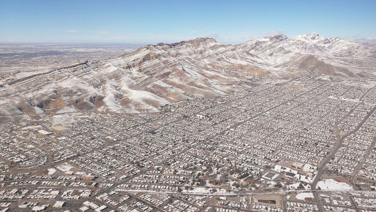 Aerial view of El Paso with the Franklin Mountains covered in snow rising behind the city grid