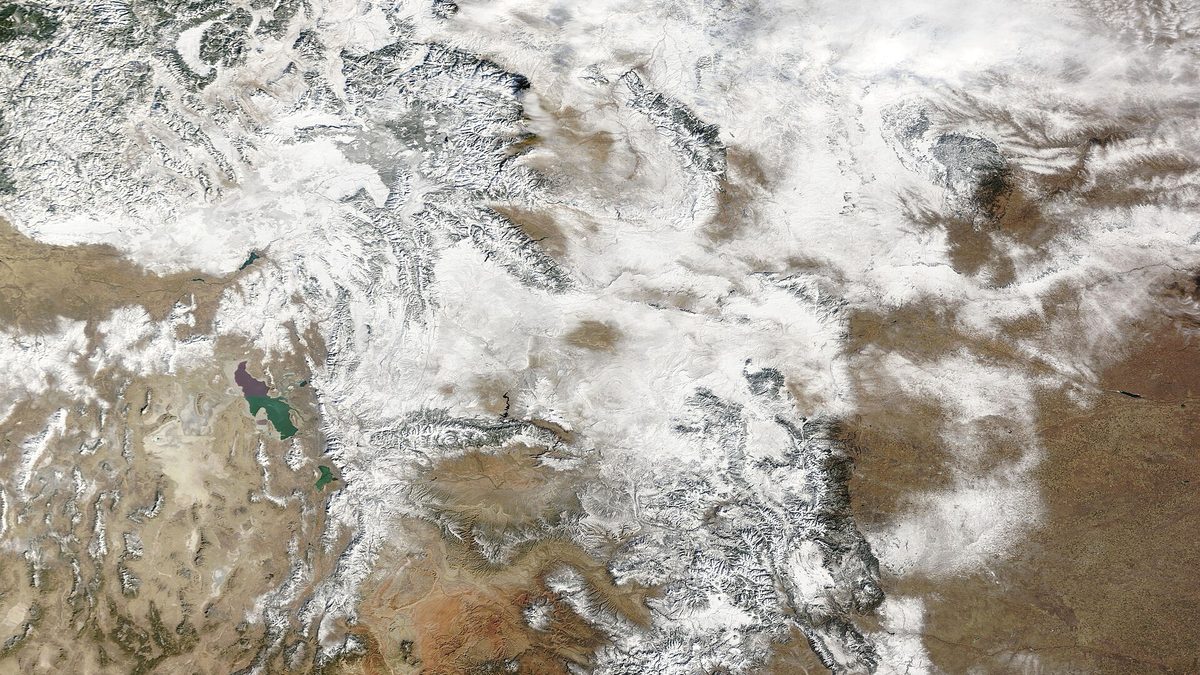 NASA satellite image of the Rocky Mountains blanketed in snow across Wyoming, Montana, Colorado, Utah and Idaho, with clear brown prairie in the surrounding lowlands
